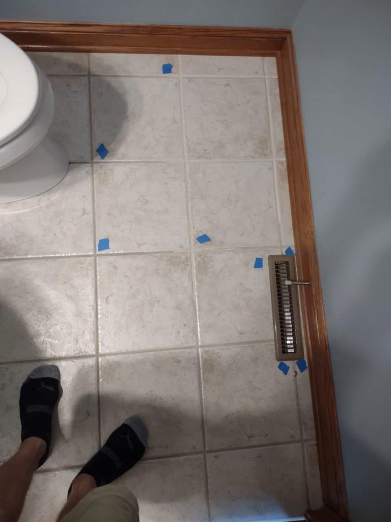 Using blue tape to mark and track the order in which the loose tiles are placed before removal.