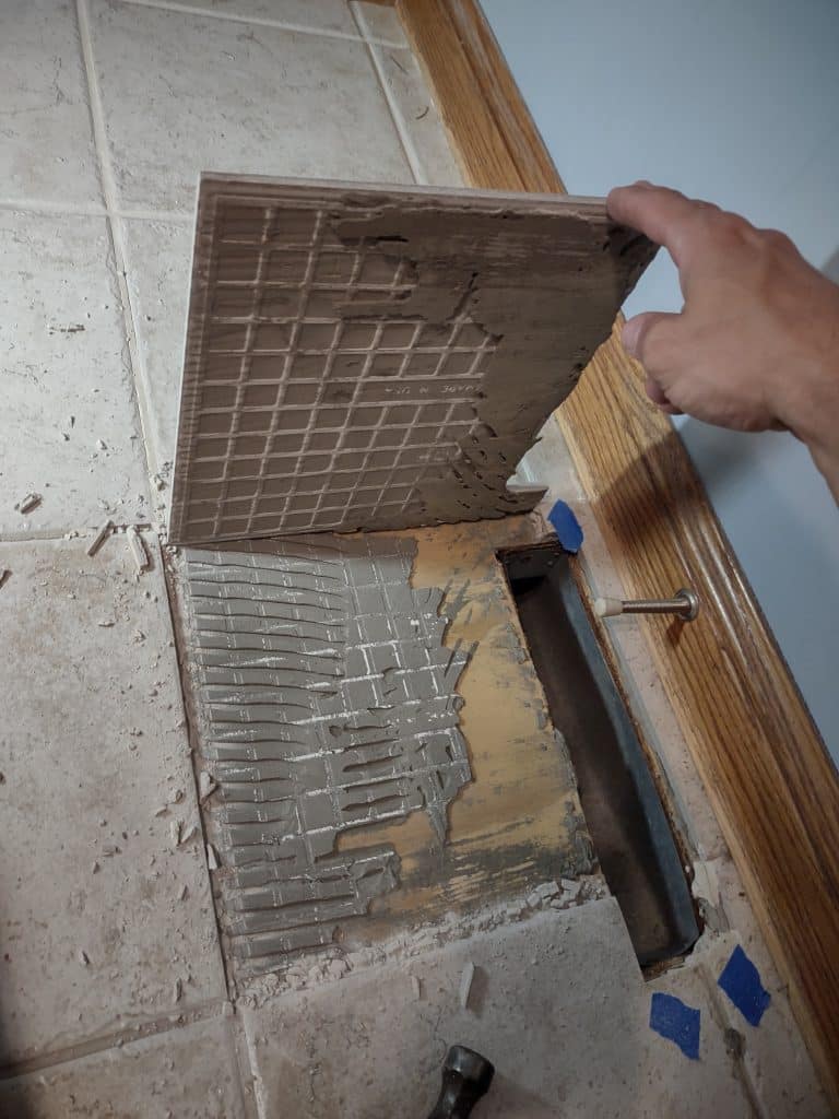 Observing the mortar coverage pattern after tile is removed.  Most of the mortar is left on the plywood substrate.